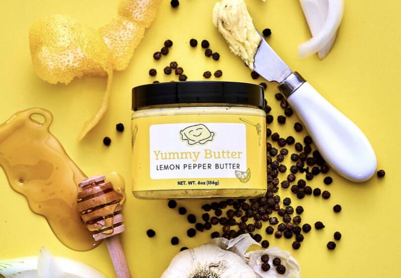 A jar of richly seasoned Lemon Pepper Butter on bright yellow background